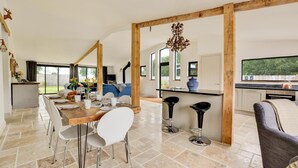 Eine geräumige Küche mit Essbereich, Holzbalken und einem großen Fenster.