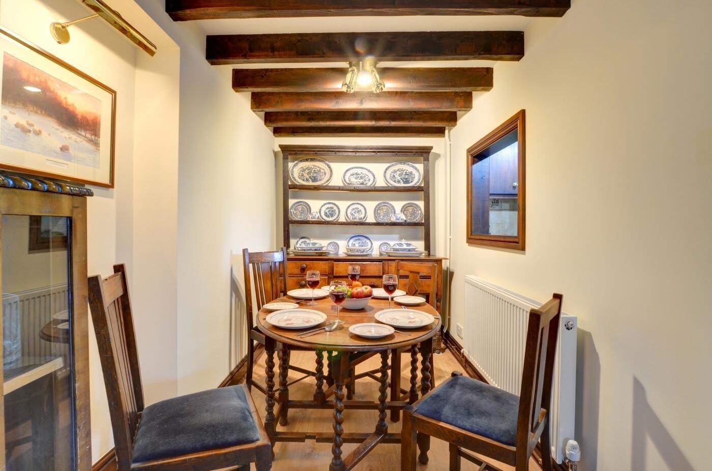 Un comedor con una mesa de madera, sillas y una pared decorada con platos.