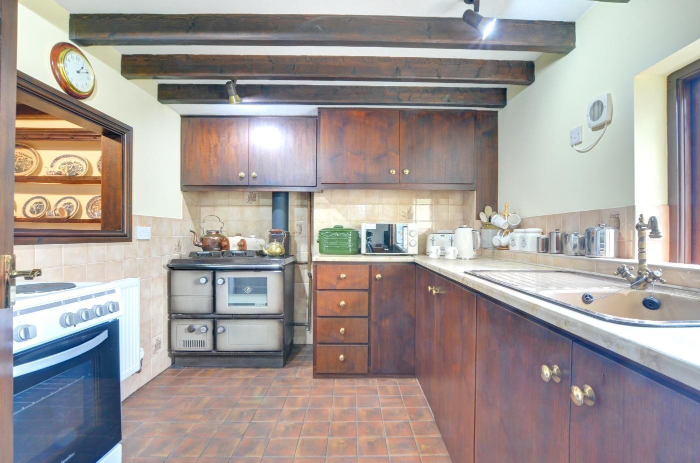 A kitchen with wooden cabinets, a stove, a microwave, and a sink.