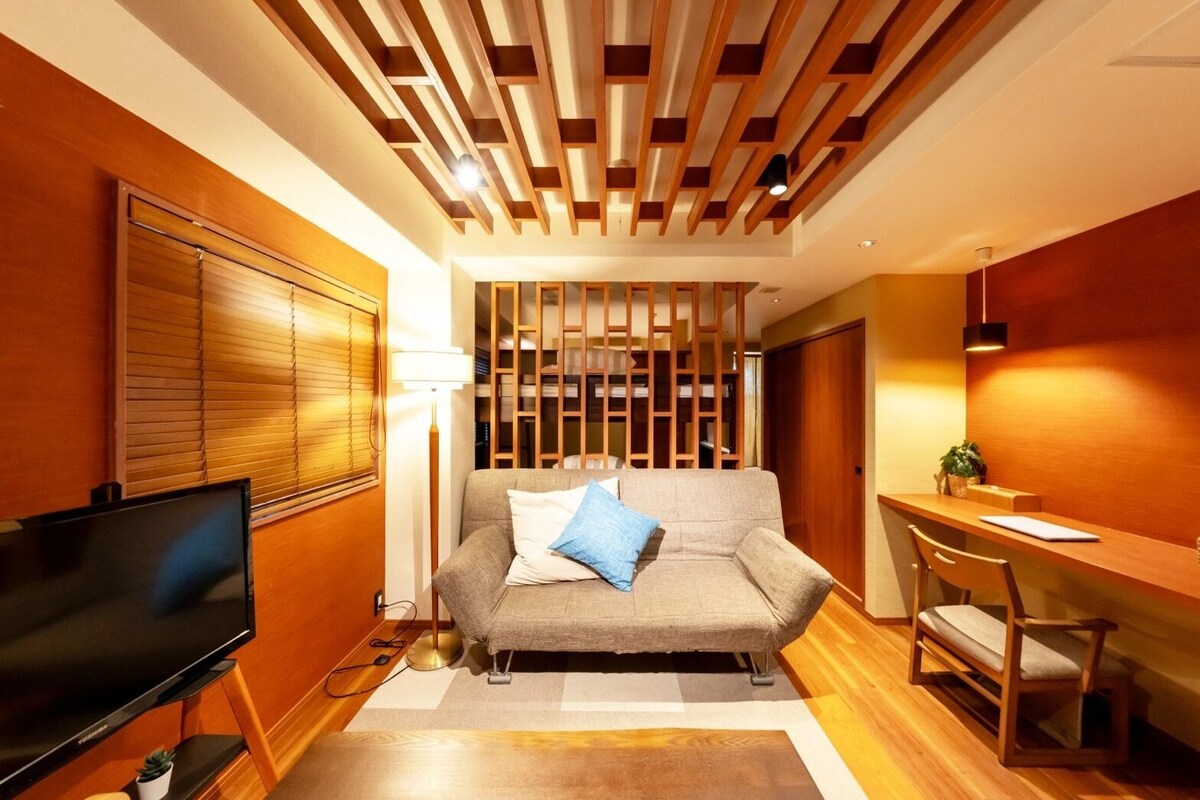 A modern living room with a sofa, TV, and wooden accents.