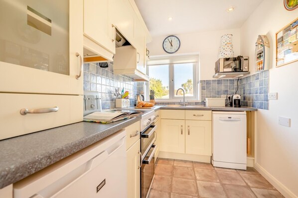 A modern kitchen with white cabinets, a built-in oven, a microwave, and a window with a view. - 2 Bed in St. Merryn (oc-p00801) (Saint Merryn)