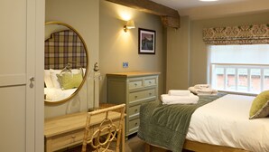 Un dormitorio con cama, cómoda, espejo, lámpara y ventana con vistas.