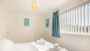Ein Schlafzimmer mit einem Bett, einem Fenster mit Jalousien und einem Gemälde an der Wand.