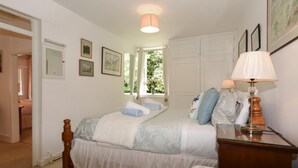 Une chambre à coucher avec un lit, une table de chevet, une lampe et des tableaux encadrés accrochés au mur.