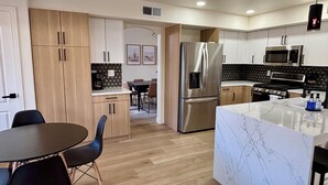 A modern kitchen with wooden cabinets, a stainless steel refrigerator, a microwave, and a marble island. - Walk to Sabino Canyon Trails, 4Bd Home with Hot Tub (Tucson)