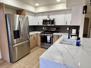A modern kitchen with stainless steel appliances, a marble countertop, and a patterned backsplash. - Walk to Sabino Canyon Trails, 4Bd Home with Hot Tub (Tucson)