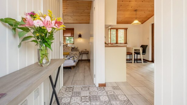 A narrow hallway leading to a bedroom with a bed, bedside table, and a vase of flowers. - 1 Bed in Milton Abbas (oc-w32019) (Milton Abbas)