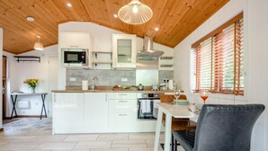 A modern kitchen with white cabinets, a central island, and a dining area with a table and chairs. - 1 Bed in Milton Abbas (oc-w32019) (Milton Abbas)