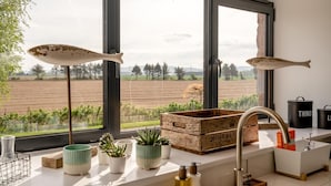 Uma cozinha com janelas amplas, um cesto de madeira e uma pia.