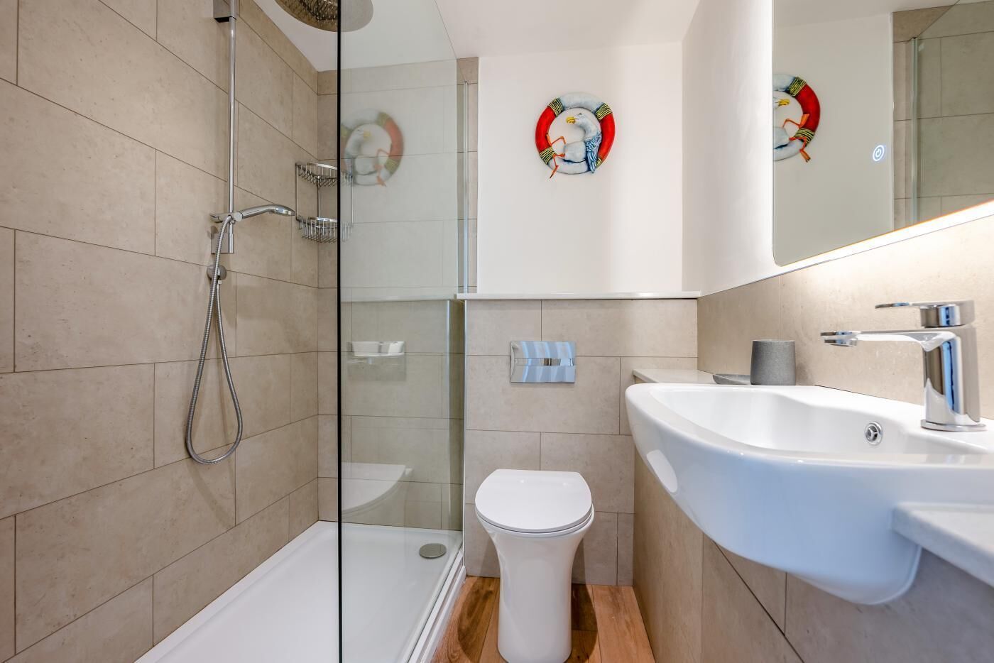 Un bagno moderno con cabina doccia in vetro, un water bianco e un lavandino bianco con rubinetto cromato.
