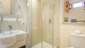 A modern bathroom with a glass-enclosed shower, a round mirror, a white sink, and a toilet. - 1 Bed in Southwold (oc-bate) (Southwold)