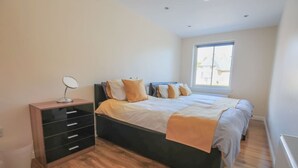 A bedroom with a bed, a dresser, a mirror, and a window. - Stylish modern newly built apartment (Edinburgh)