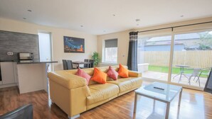 A modern living room with a sofa, coffee table, and a dining area. - Stylish modern newly built apartment (Edinburgh)