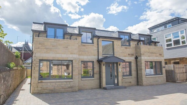 A two-story house with a stone facade, large windows, and a dark-colored entrance. - Stylish modern newly built apartment (Edinburgh)