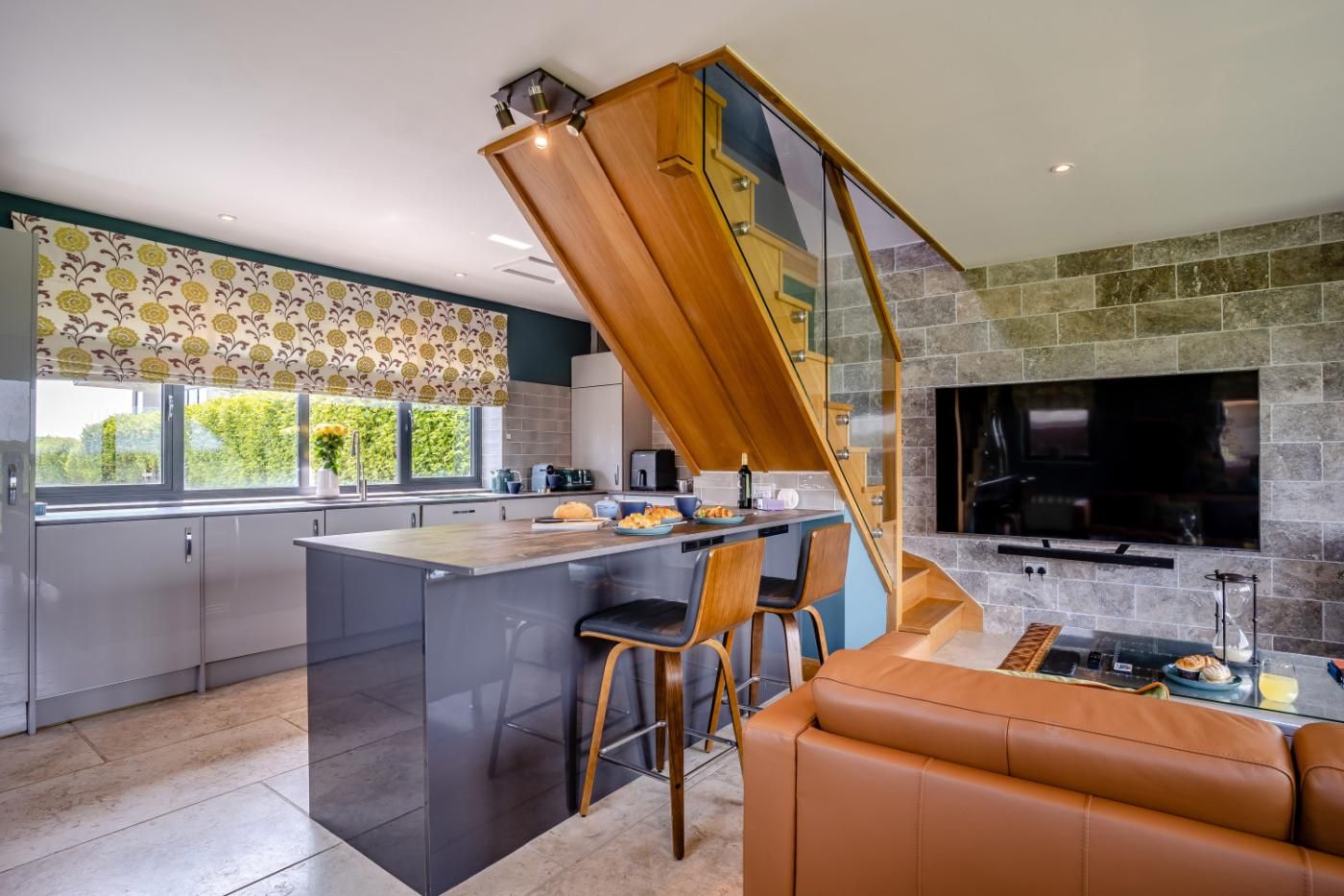 A modern kitchen with a central island, a dining area with a sofa, and a stone fireplace.