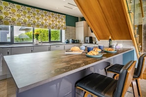Una cucina moderna con una grande isola, sgabelli da bar e vista sul verde.