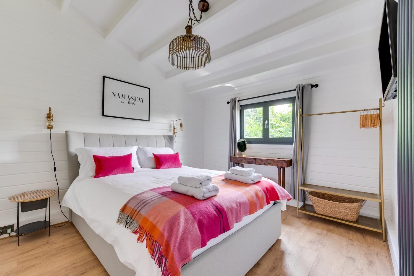 Ein modernes Schlafzimmer mit einem großen Bett, einem Nachttisch, einer Pendelleuchte und einem Fenster mit Vorhängen.