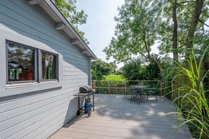 En terrasse med grill, udendørs møbler og udsigt til en have.