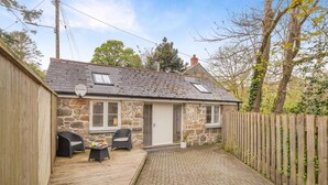 A stone cottage with a tiled patio, two wicker chairs, a small table, and a wooden fence. - 1 Bed in Lamorna (oc-k31904) (Lamorna)