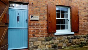 A brick building with a blue door and a window with wooden shutters. A sign on the wall reads "Custom House Steps, Harbour View." - 2 Bed in Scarborough (oc-s027) (Scarborough)