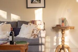 A living room with a sofa, pillows, a small wooden table, and a bookshelf. - 1 Bed in Helmsley (oc-l32034) (Helmsley)