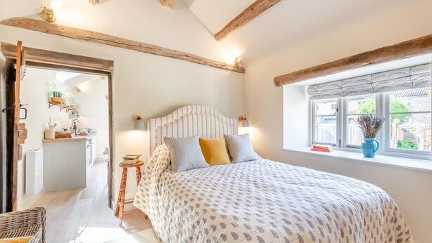 A bedroom with a bed, bedside table, lamp, and a window with a view.