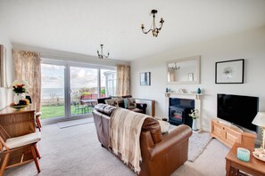 A spacious living room with a fireplace, a television, and a view of the outdoors. - 2 Bed in Scarborough (oc-s037) (Osgodby)