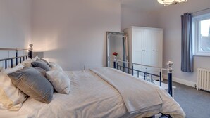 Een slaapkamer met een bed, een spiegel, een kast en een raam met gordijnen.