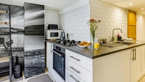 Et moderne køkken med hvide skabe, en sort bordplade, en mikrobølgeovn, en brødrister og en vask.