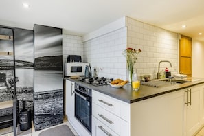 Eine moderne Küche mit weißen Schränken, einer schwarzen Arbeitsplatte, einer Mikrowelle, einem Toaster und einem Spülbecken.