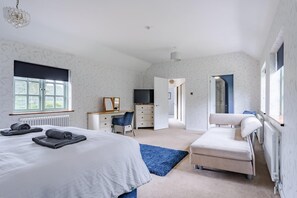 A bedroom with a bed, a desk, a chair, a TV, and a bathroom.