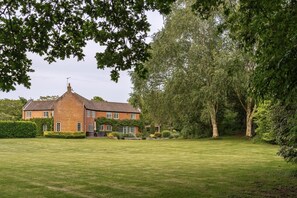 A large brick house with a well-maintained lawn and mature trees.