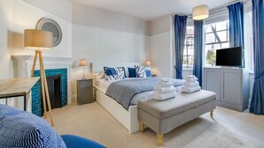 Une chambre à coucher moderne avec un lit, des tables de chevet, une télévision et une cheminée.