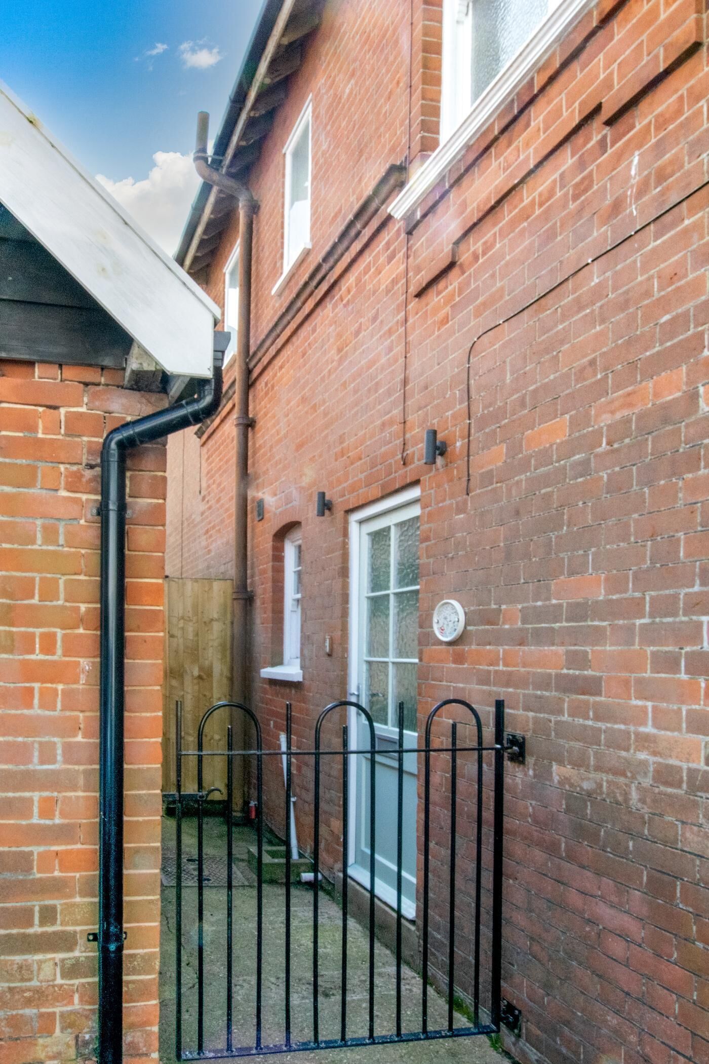 A brick building with a metal gate, a window, and a visible door.