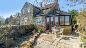 A stone house with a conservatory, a stone wall, and a patio with a table and chairs. - 4 Bed in Onecote (oc-b31731) (Onecote)