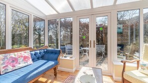 A conservatory with a blue sofa, a dining table, and a chair. - 4 Bed in Onecote (oc-b31731) (Onecote)