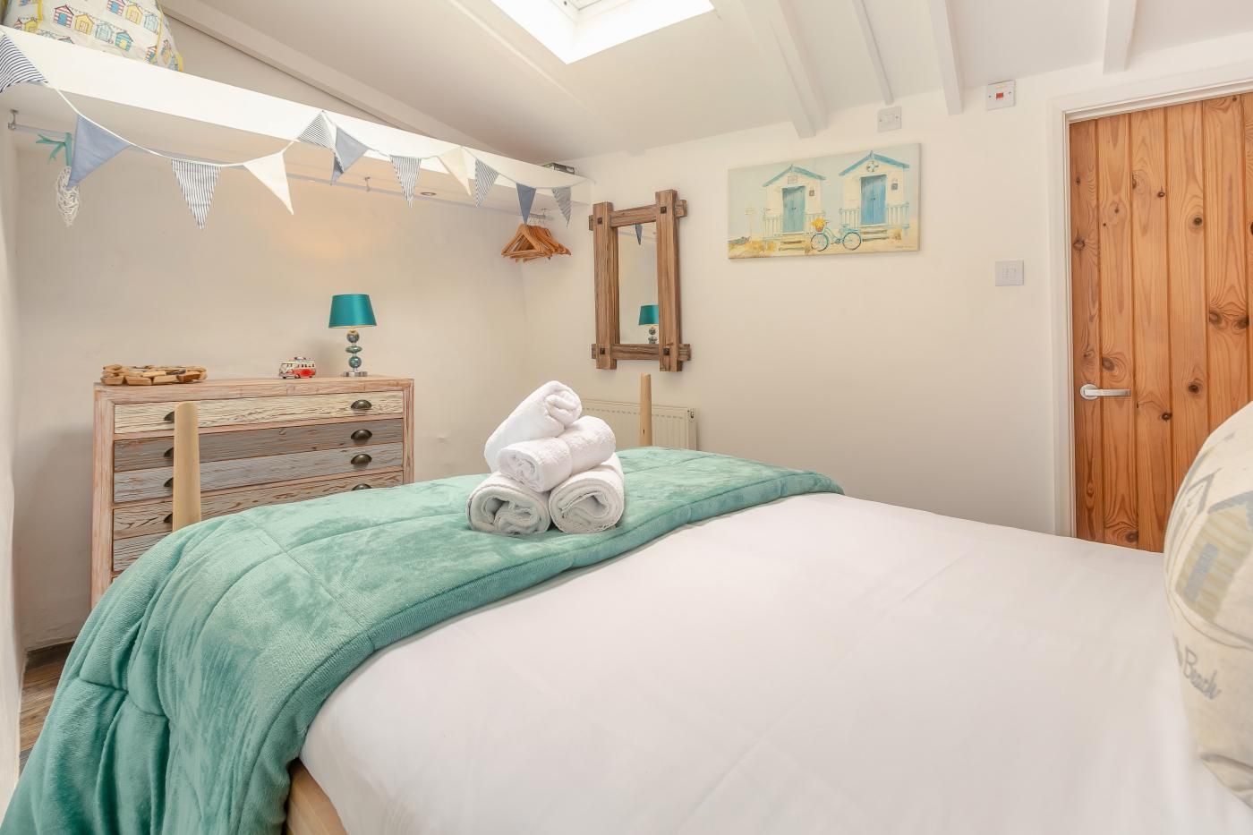 Quarto com uma cama, cômoda de madeira, espelho e um quadro na parede.