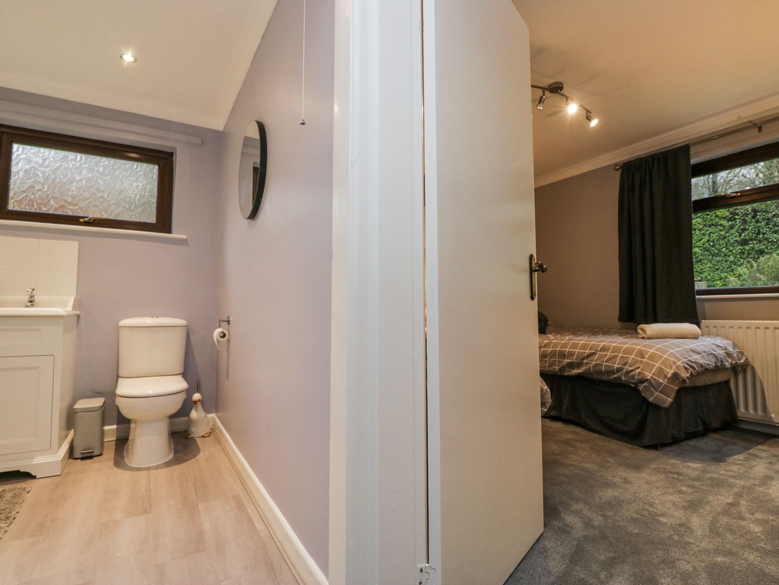 Ein Schlafzimmer mit Bett, einem fenster mit Vorhängen, einer Heizung und einem Badezimmer mit Toilette und Waschbecken.