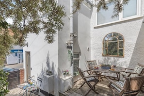 Eine Terrasse mit Tisch und Stühlen, umgeben von weißen Wänden und einem Fenster.