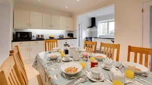 A modern kitchen with white cabinets, a black countertop, and a dining area with a table set for breakfast.