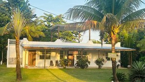 A guest house with a corrugated metal roof, a front porch with a hammock, and a sign indicating it is a guest house. - Beach view, Hammocks on roof, Quick walk to beach (Hopkins)