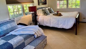 A bedroom with two beds, a sofa, a lamp, and a painting. - Beach view, Hammocks on roof, Quick walk to beach (Hopkins)