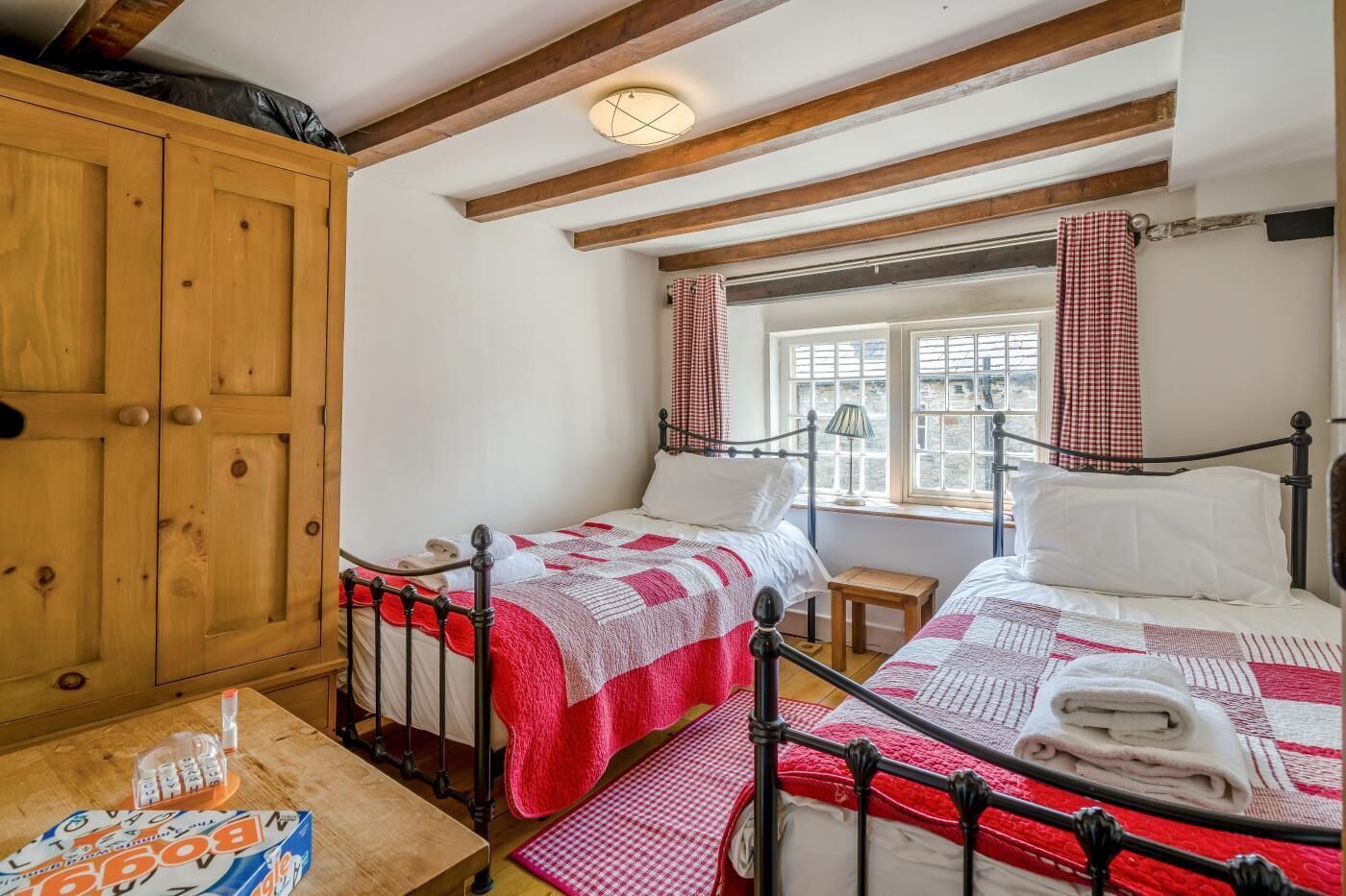Ein Schlafzimmer mit zwei Betten, einem Holzschrank und einem Fenster mit Vorhängen.