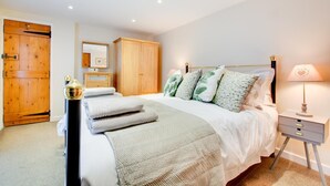 Une chambre à coucher comprenant un lit, une table de chevet, une lampe, une armoire en bois et un miroir.