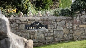 Un muro de piedra con un letrero que dice "Croft Acre".