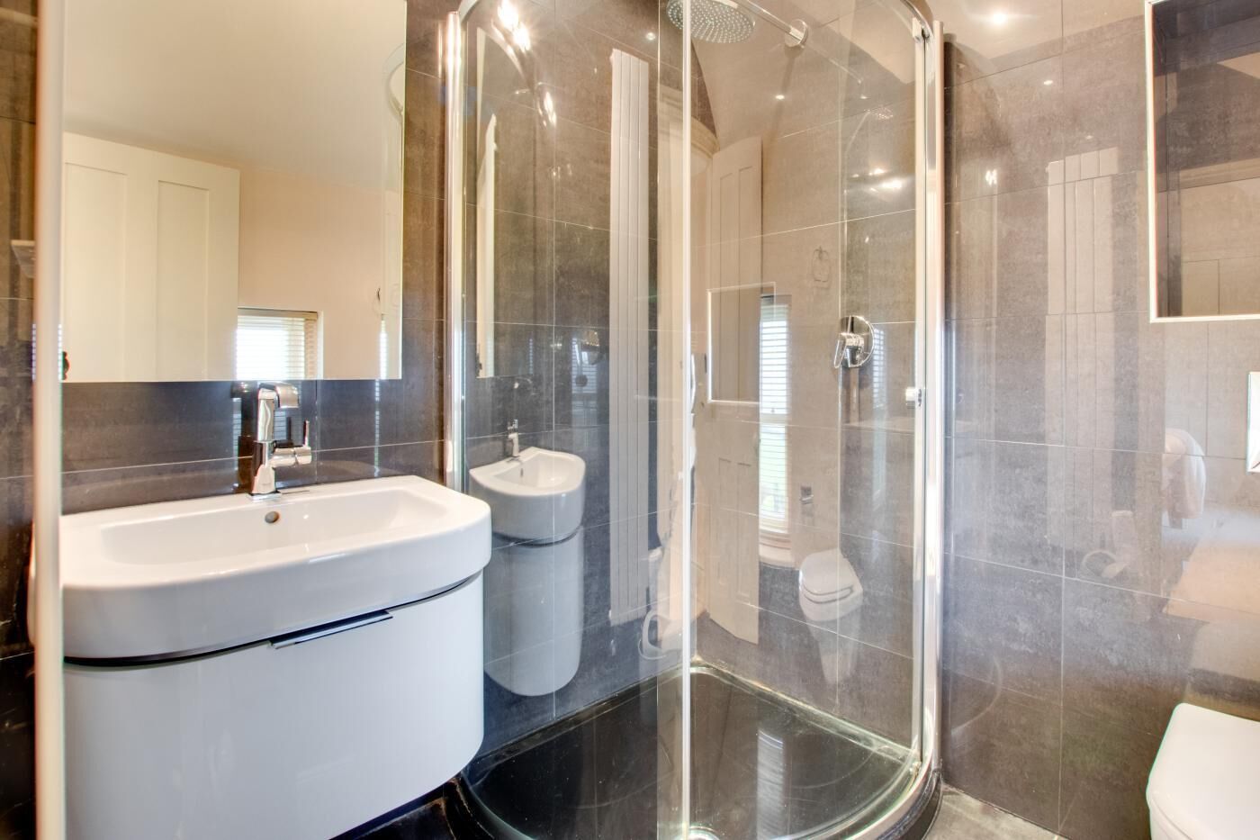 Une salle de bain moderne avec une douche à parois de verre, un grand lavabo et un bidet.