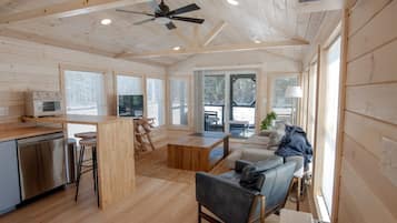 A spacious living area with a wooden ceiling, a sofa, a coffee table, and a television.