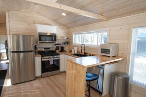 A compact kitchen with a refrigerator, stove, microwave, and oven. - Pine Marten Cabin (Pittsburg)