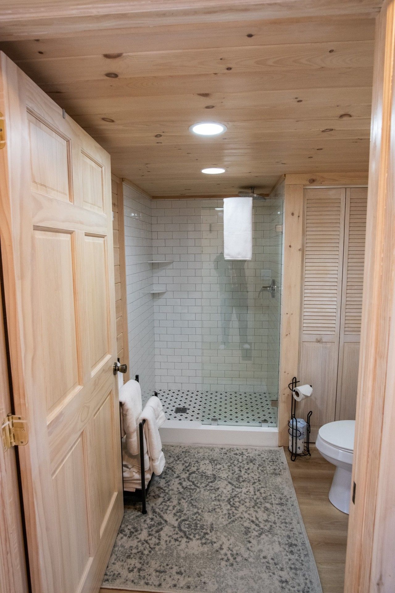 Ein Badezimmer mit Holzwandverkleidung, einer Dusche, einer Toilette und einem Handtuchhalter.