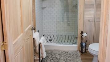 Ein Badezimmer mit Holzwandverkleidung, einer Dusche, einer Toilette und einem Handtuchhalter.